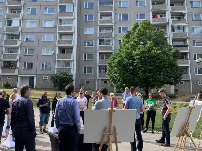 Tipsport liga cover photo pre case study na ktorej je záber na stretnutie obyvateľov sídliska na ulici, kde sa prezentujú informácie o projekte.